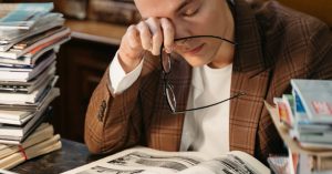 Tired student rubbing eyes at desk with books for burnout signs among competitive exam students.