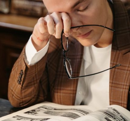 Tired student rubbing eyes at desk with books for burnout signs among competitive exam students.
